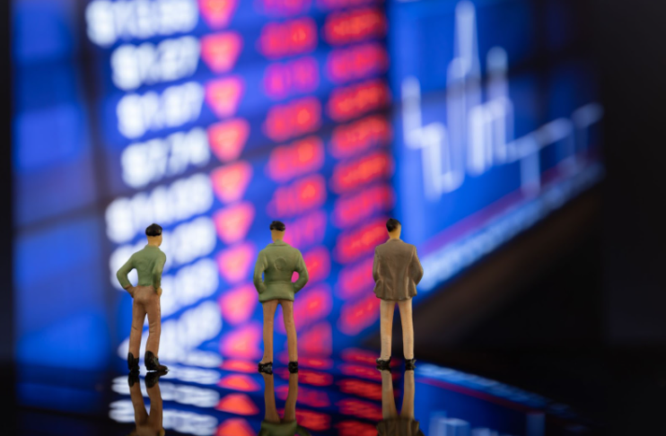Three miniature investors analyzing red-falling stock prices on a digital board, concept of CFD investing indices and market downturn.