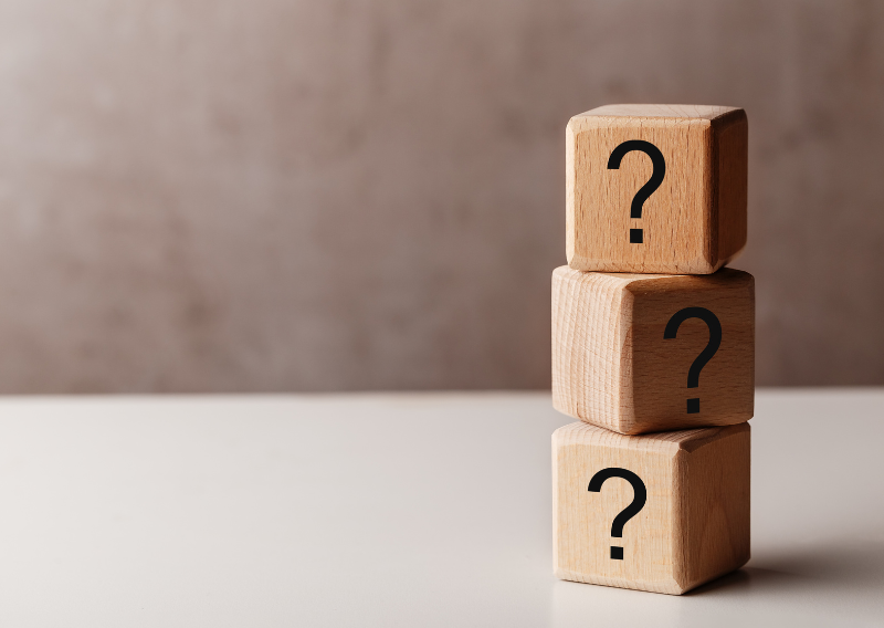 Three stacked wooden blocks with question marks, representing market uncertainty and the decision-making process faced by forex traders in Singapore.